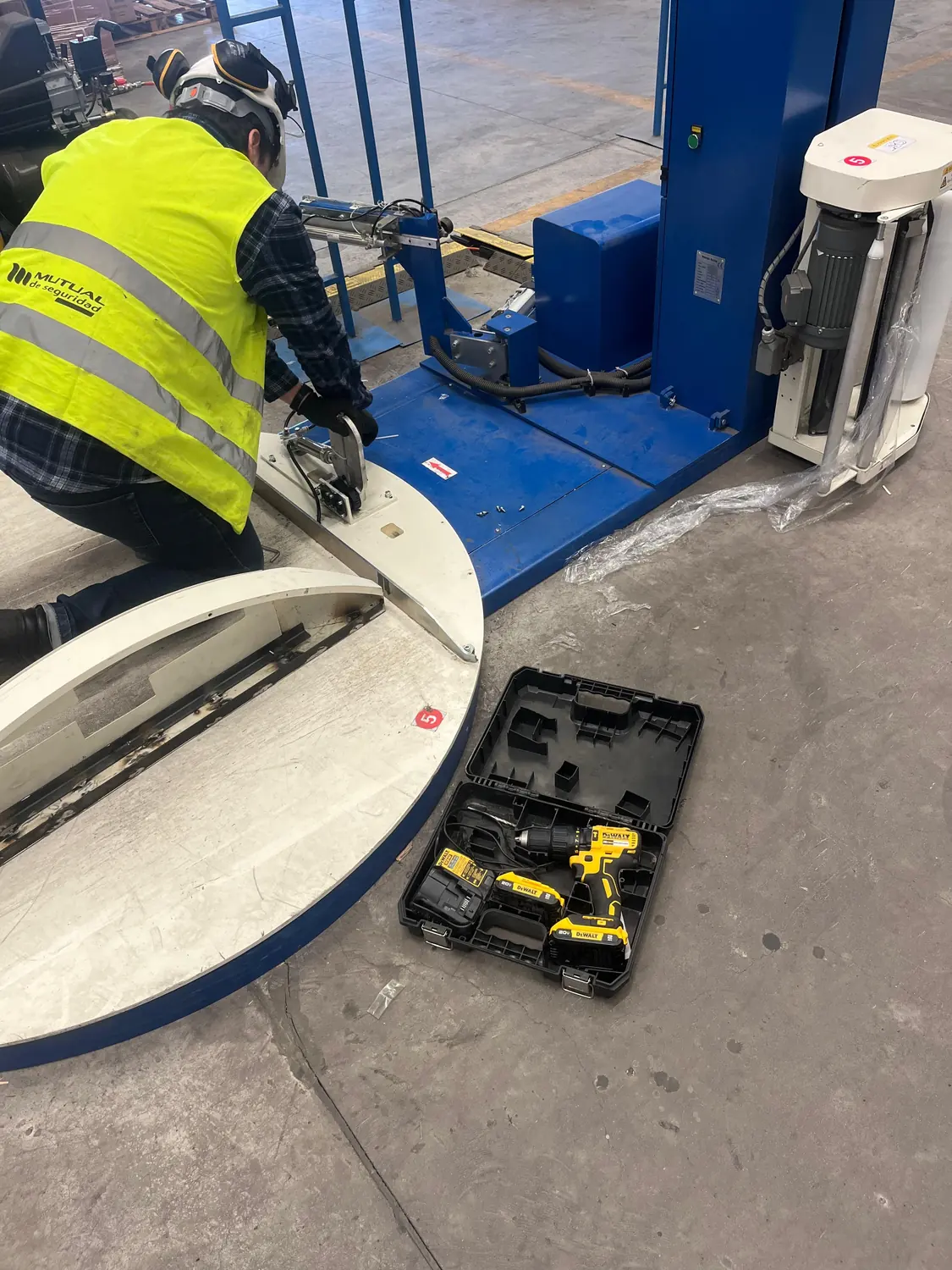 Técnico desmontando el plato de una envolvedora con herramienta eléctrica
